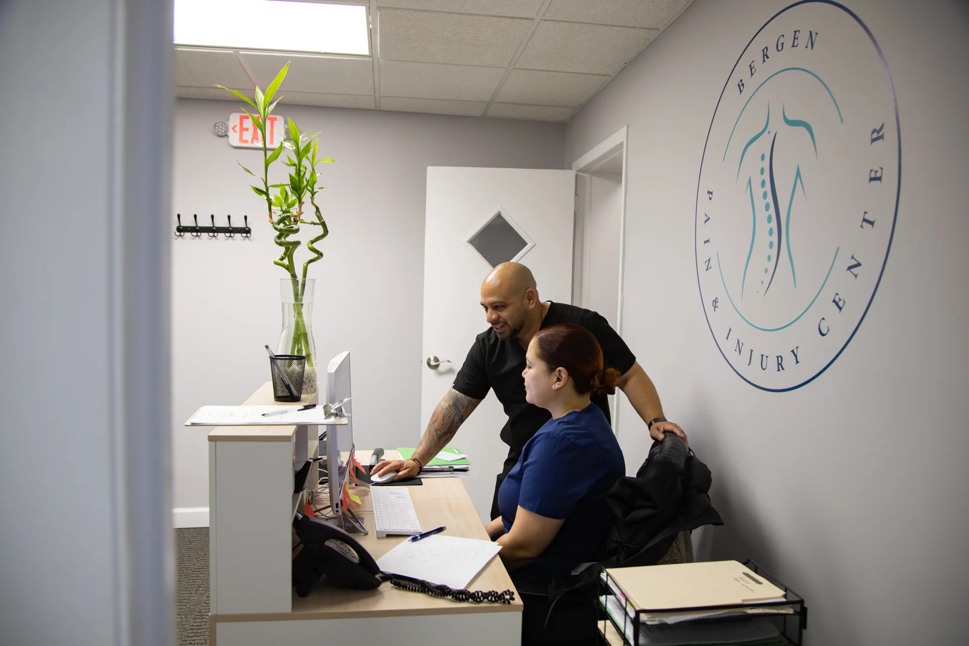 Clinic staff helping a patient with the intake paperwork at the front desk