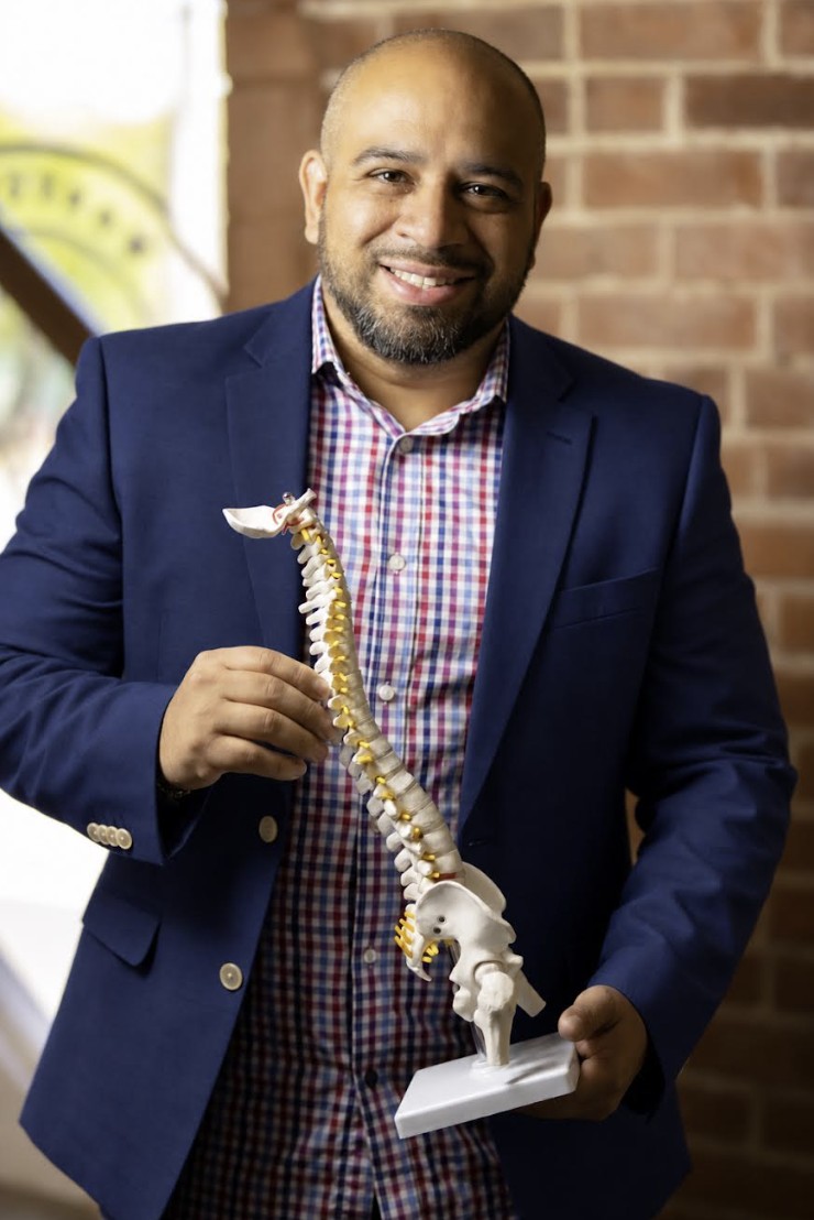 Dr. Jorge De La Torre holding a spine model